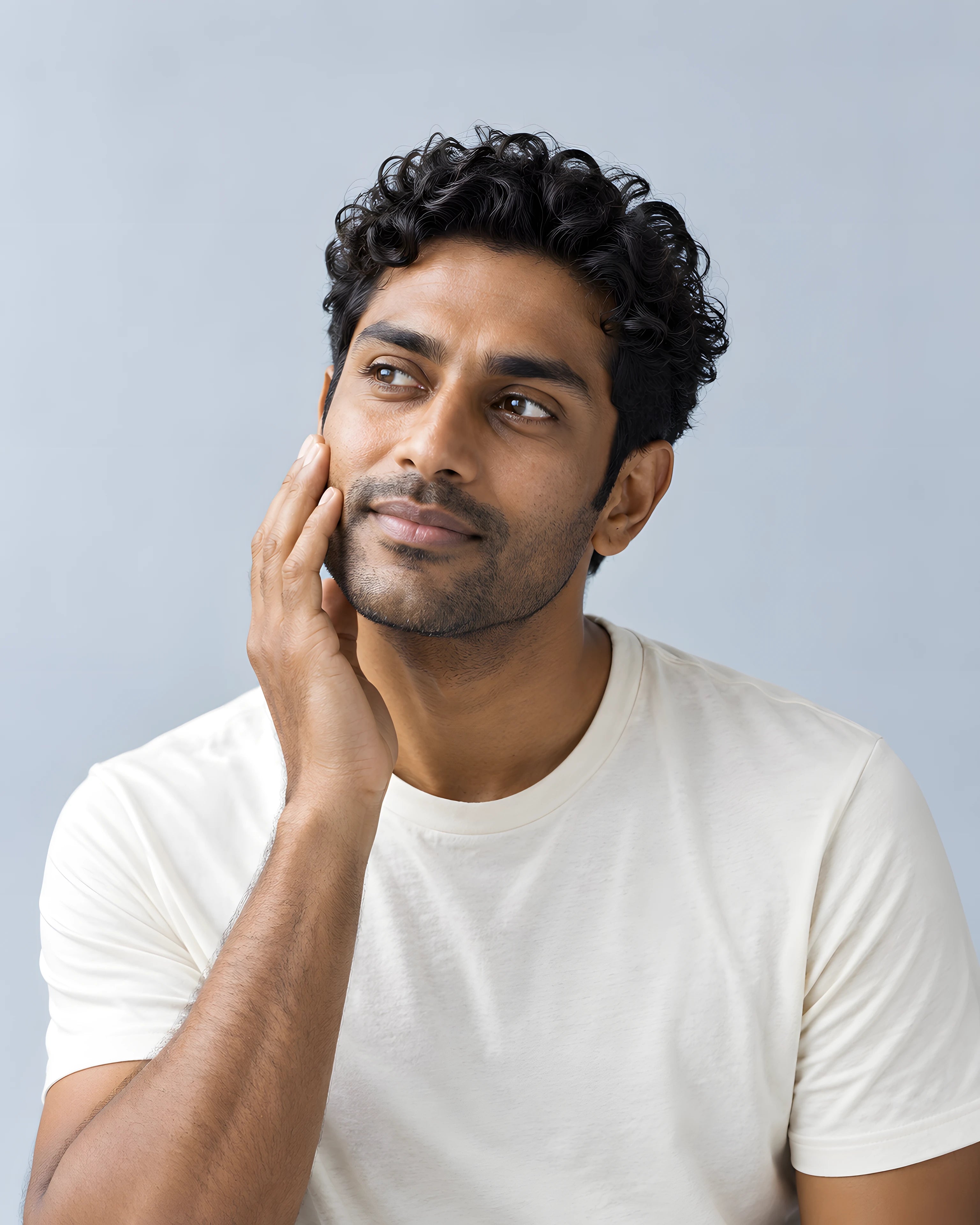 A man gently touching his cheek in soft daylight