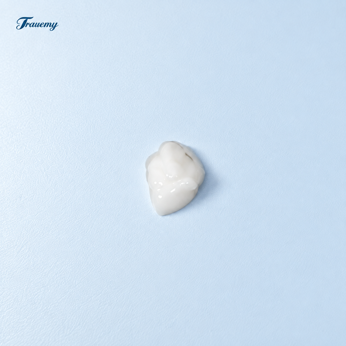 TRAUER Bioactive Collagen Soothing Barrier Cream texture: a small opaque off-white cream sample on a cool pale-blue surface